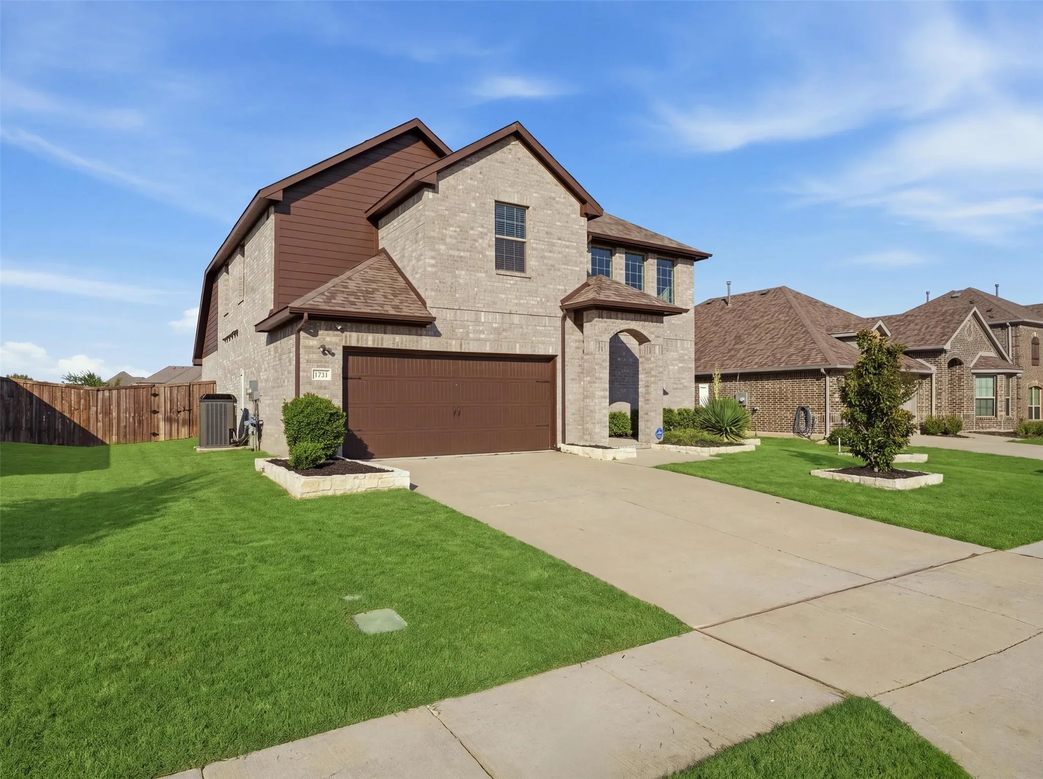 Brick exterior with horizontal siding accents, an arched entry, a two-car garage, and a concrete driveway