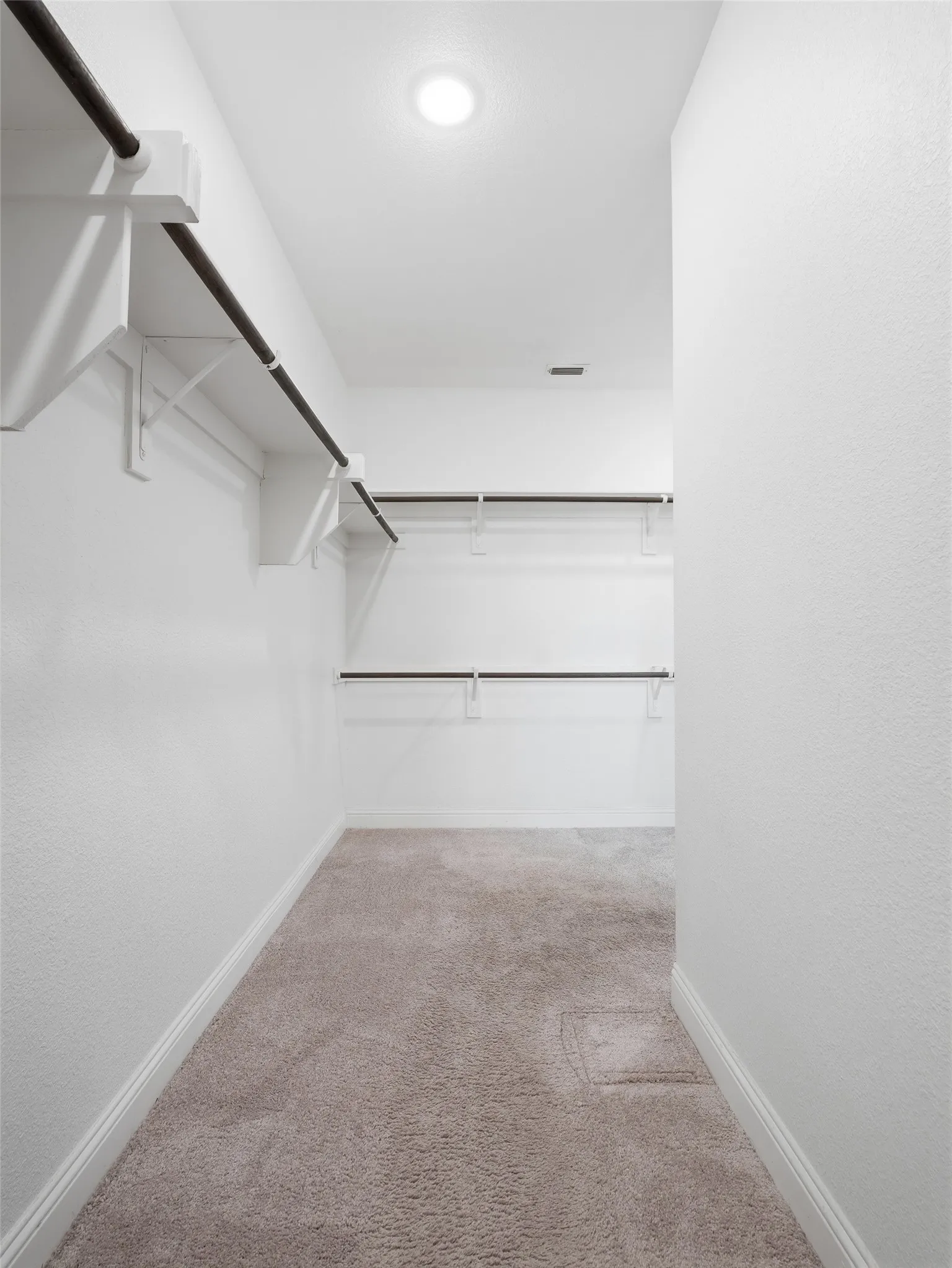 Walk-in closet featuring built-in shelving, garment rods, recessed lighting, and carpet flooring