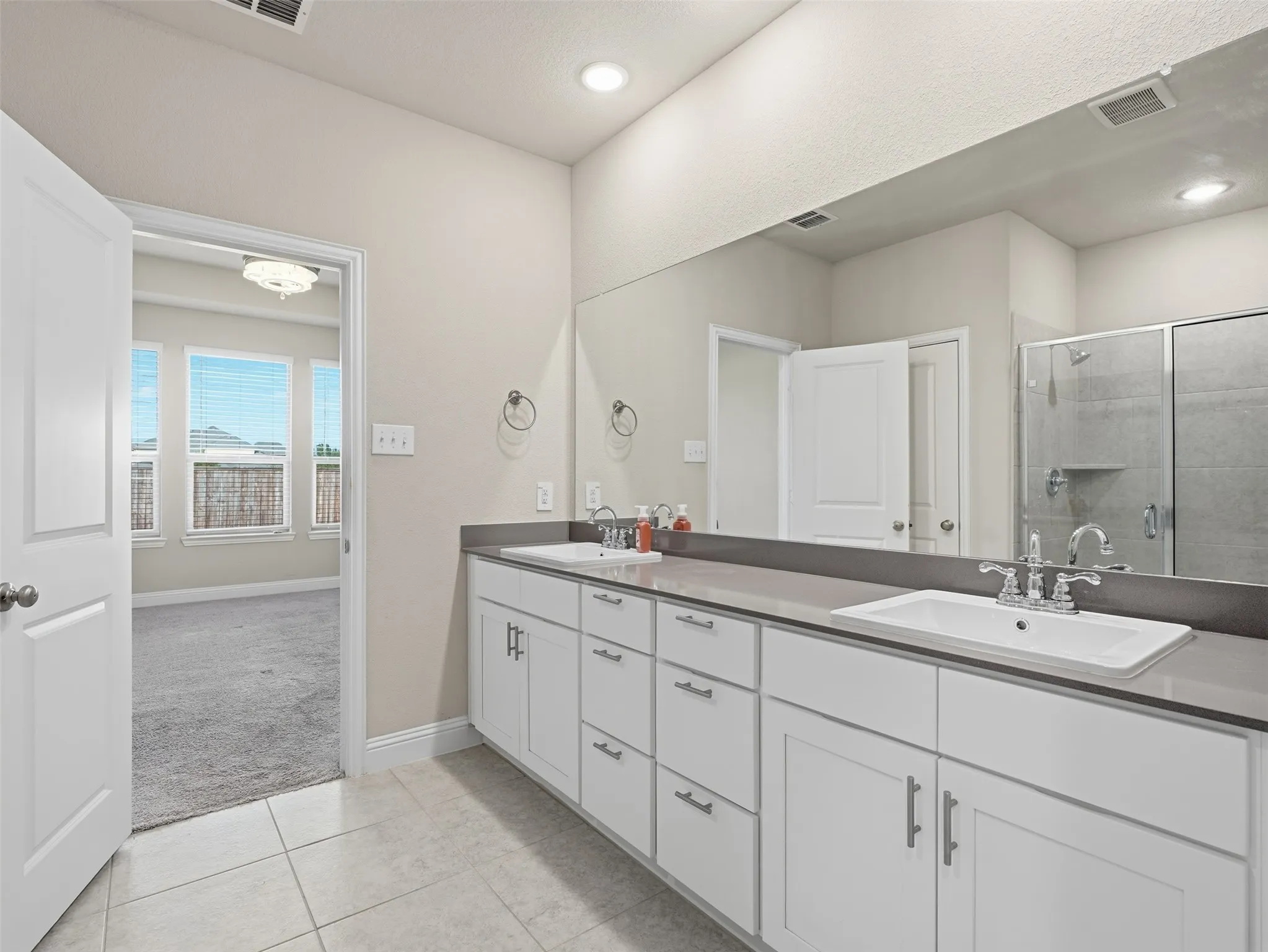 Double vanity with undermount sinks, stone countertop, and ample cabinet storage
