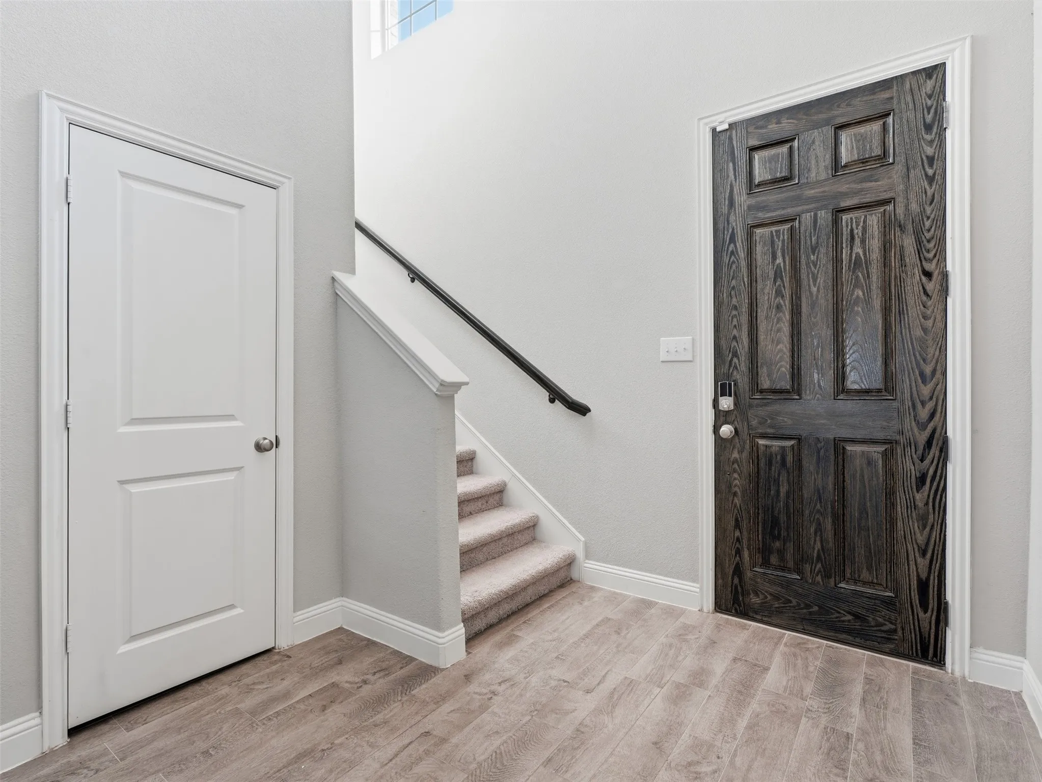 Wood-finish flooring with a multi-panel door and a carpeted staircase