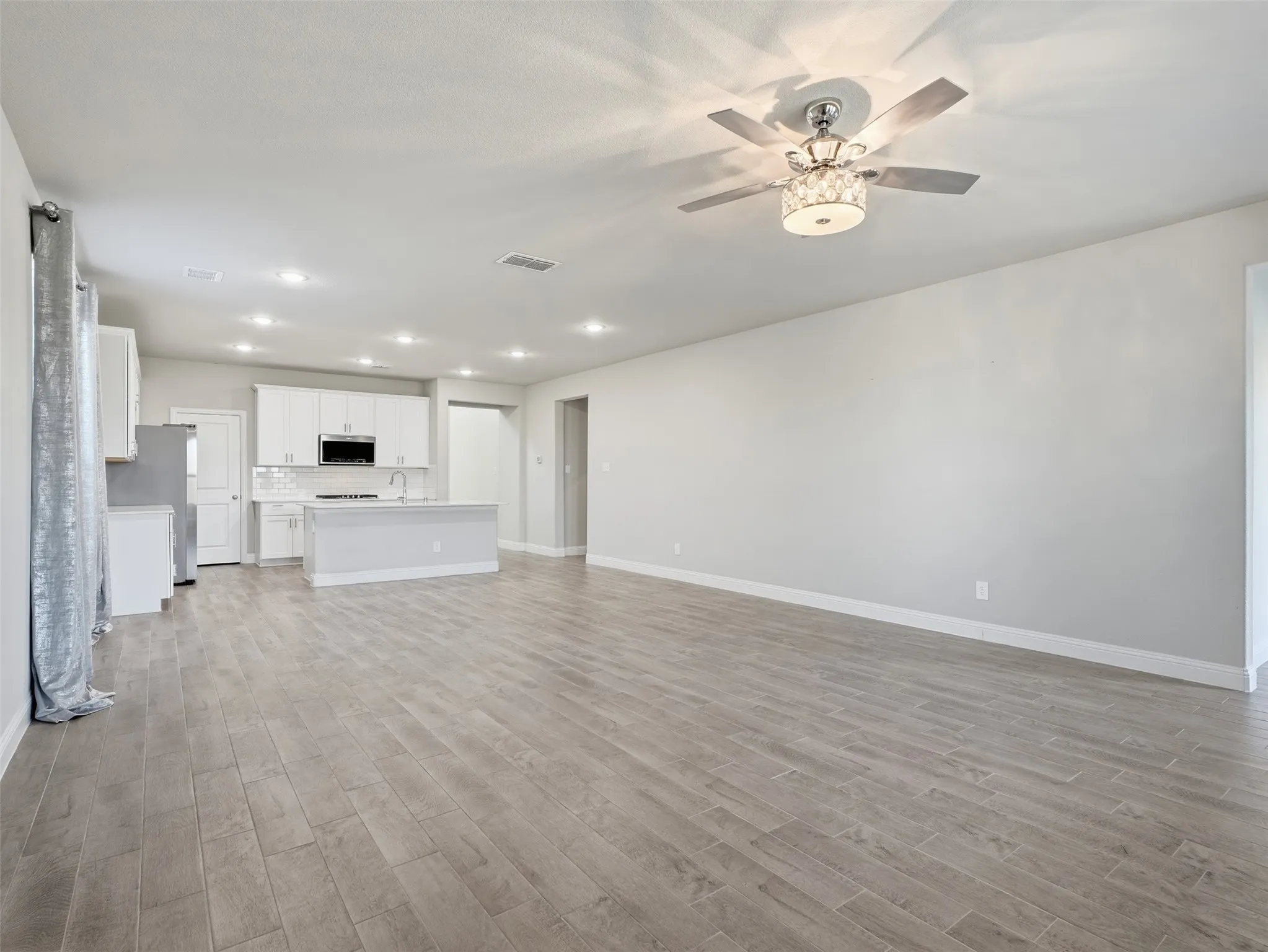 Open-concept living area featuring wood-finish plank flooring, recessed ceiling lighting, and a ceiling fan with integrated light fixture