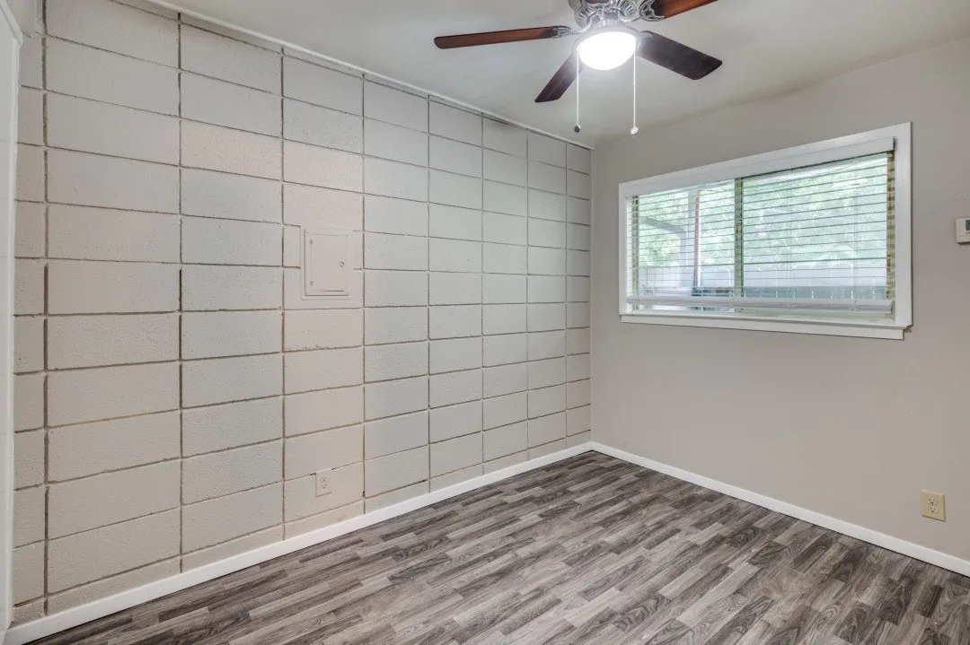 Wood-finish flooring, a window with blinds, and a ceiling fan with integrated lighting