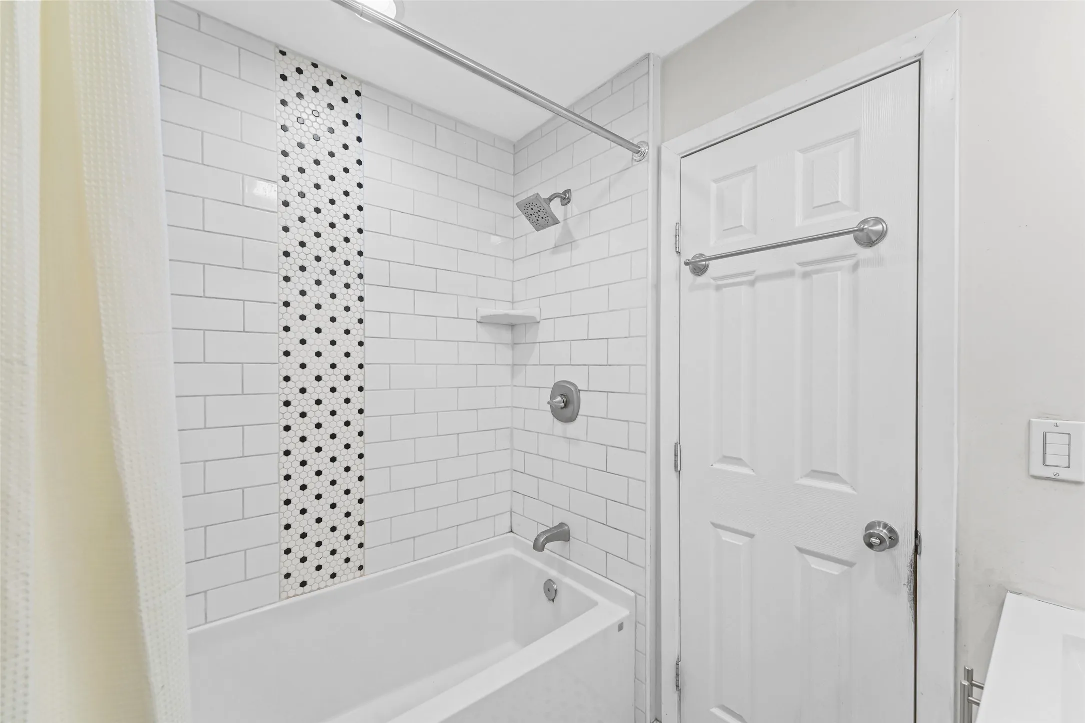 White subway tile shower surround with a decorative mosaic tile inlay and a built-in shower shelf