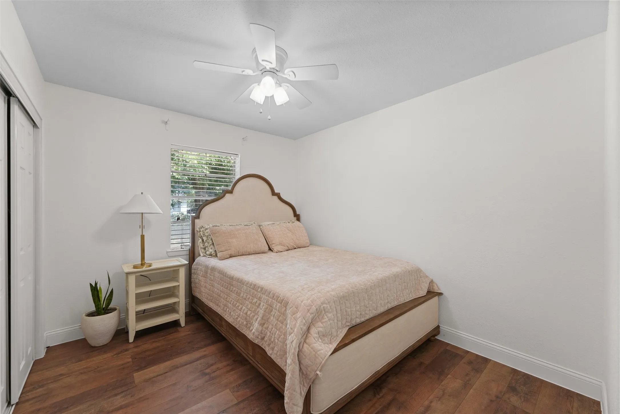 Wood-finish flooring, white walls, and a ceiling fan with integrated lighting
