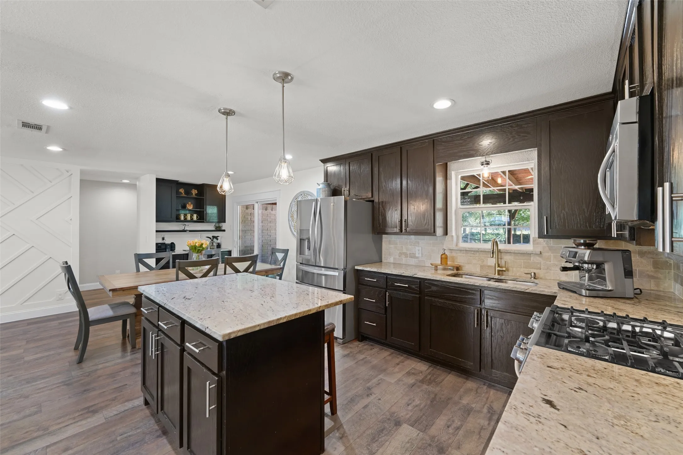 Kitchen featuring dark wood-finish cabinetry, light-toned countertops, stainless steel appliances, and a tile backsplash