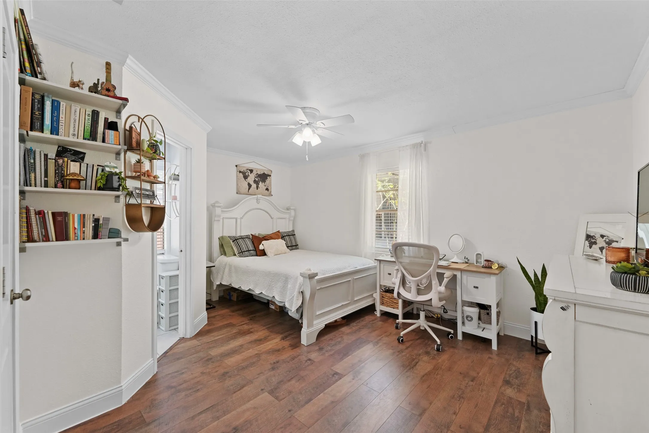 Wood-finish flooring throughout, white wall paint, crown molding, double window with white blinds, and a ceiling fan with light fixture