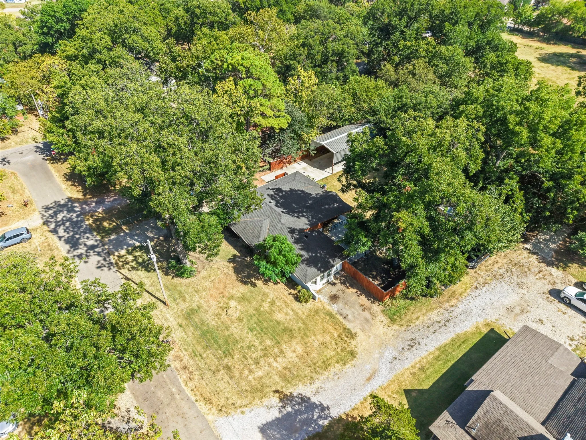 Spacious lot featuring mature trees, a detached outbuilding, and a gravel driveway