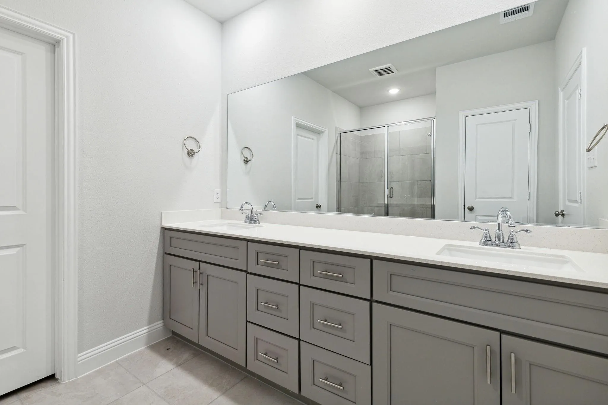 Bathroom featuring vanity, tile patterned floors, and a shower with door