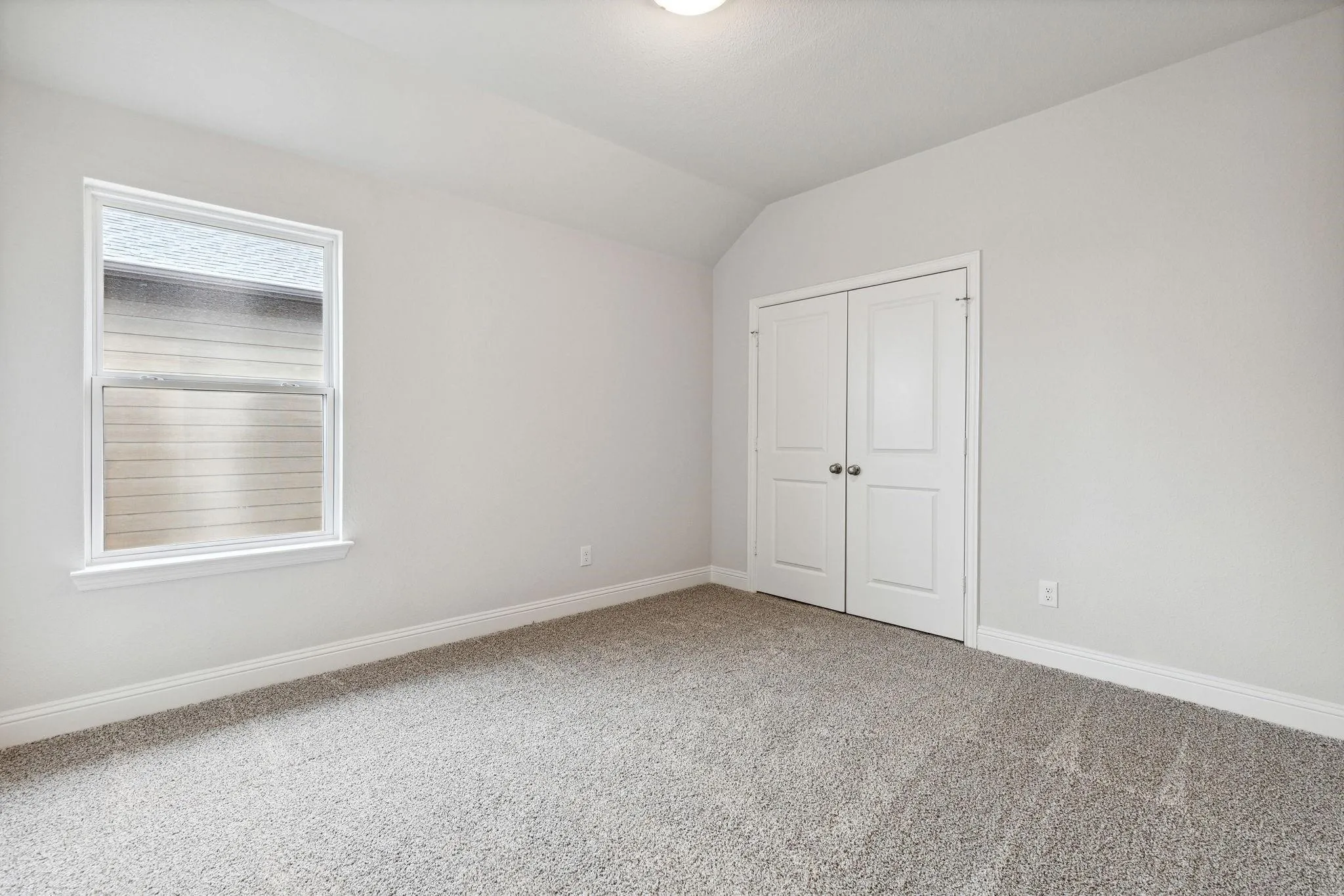 Unfurnished bedroom featuring a closet, carpet, and vaulted ceiling