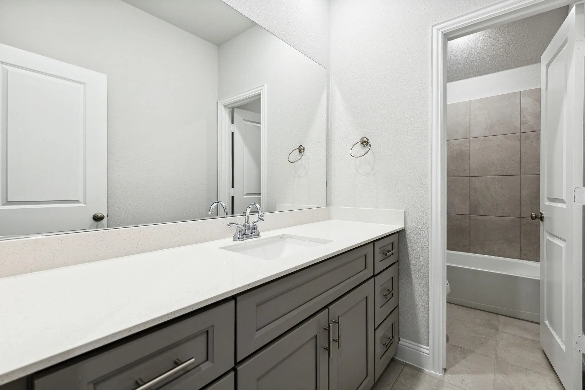 Full bathroom with vanity, toilet, tiled shower / bath combo, and tile patterned flooring