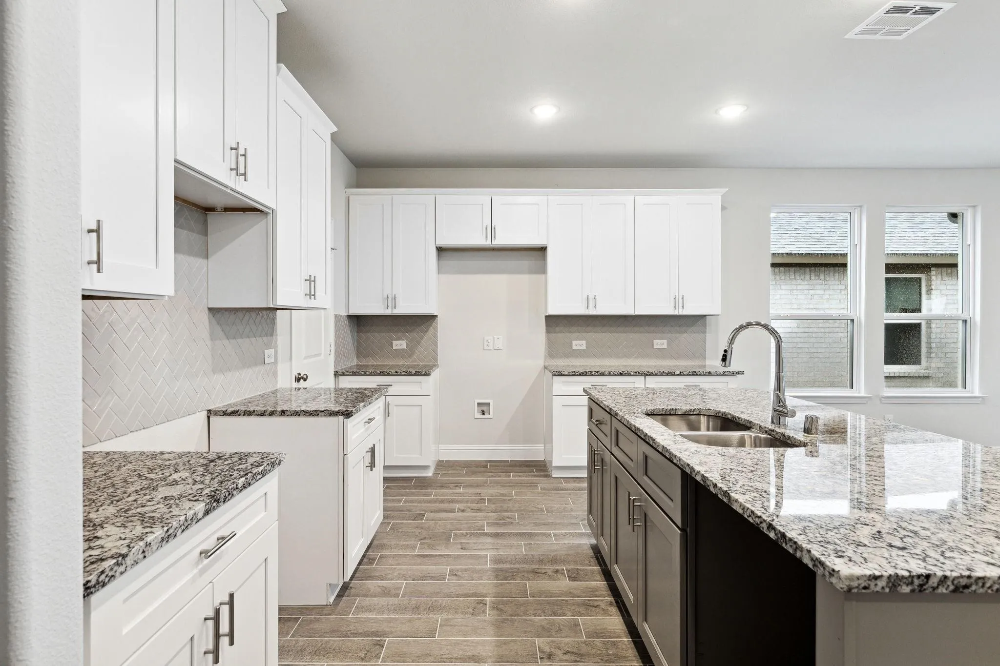 Kitchen featuring light hardwood / wood-style flooring, white cabinetry, light stone countertops, and sink