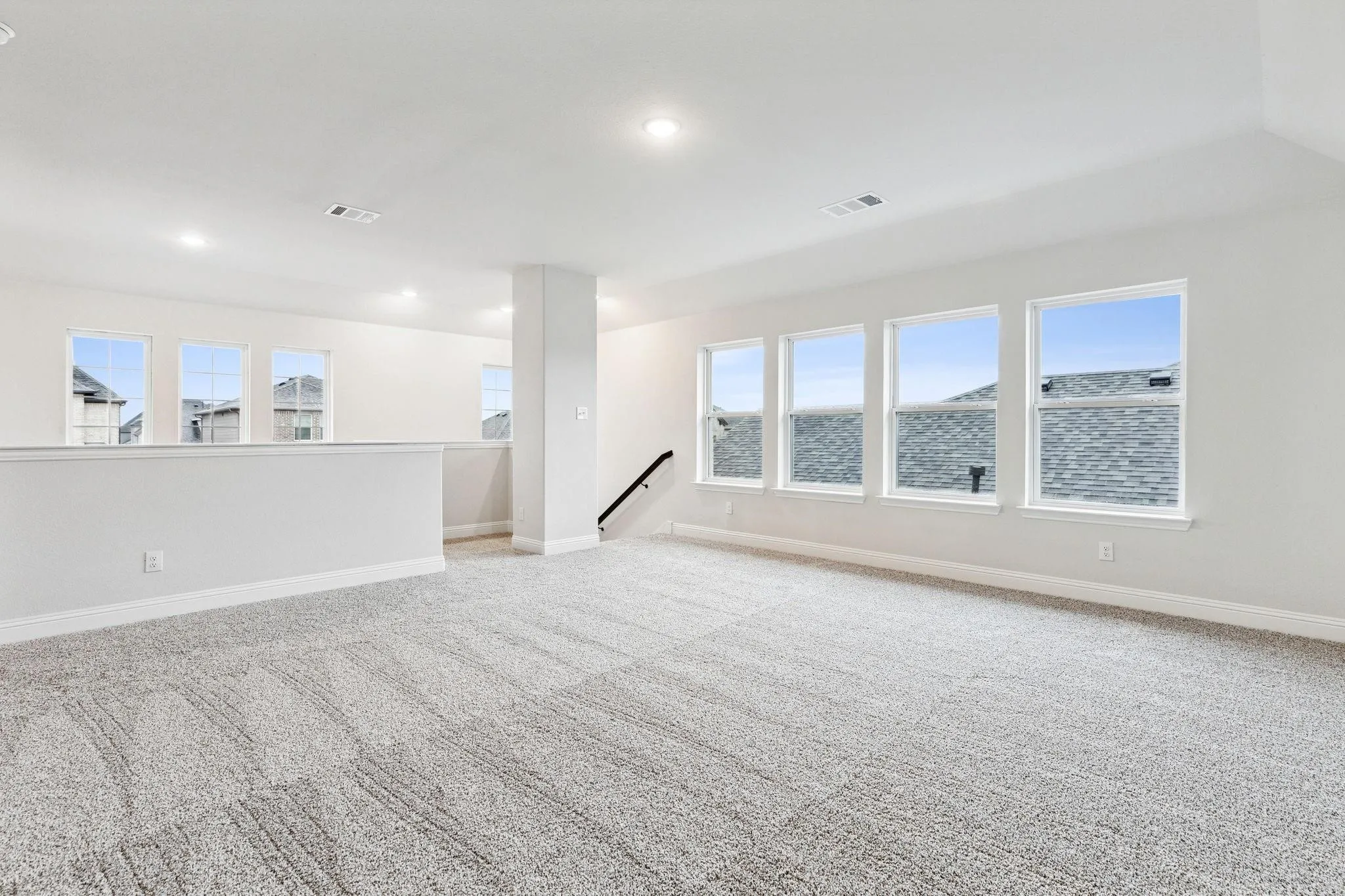 Empty room featuring lofted ceiling, a water view, and light colored carpet