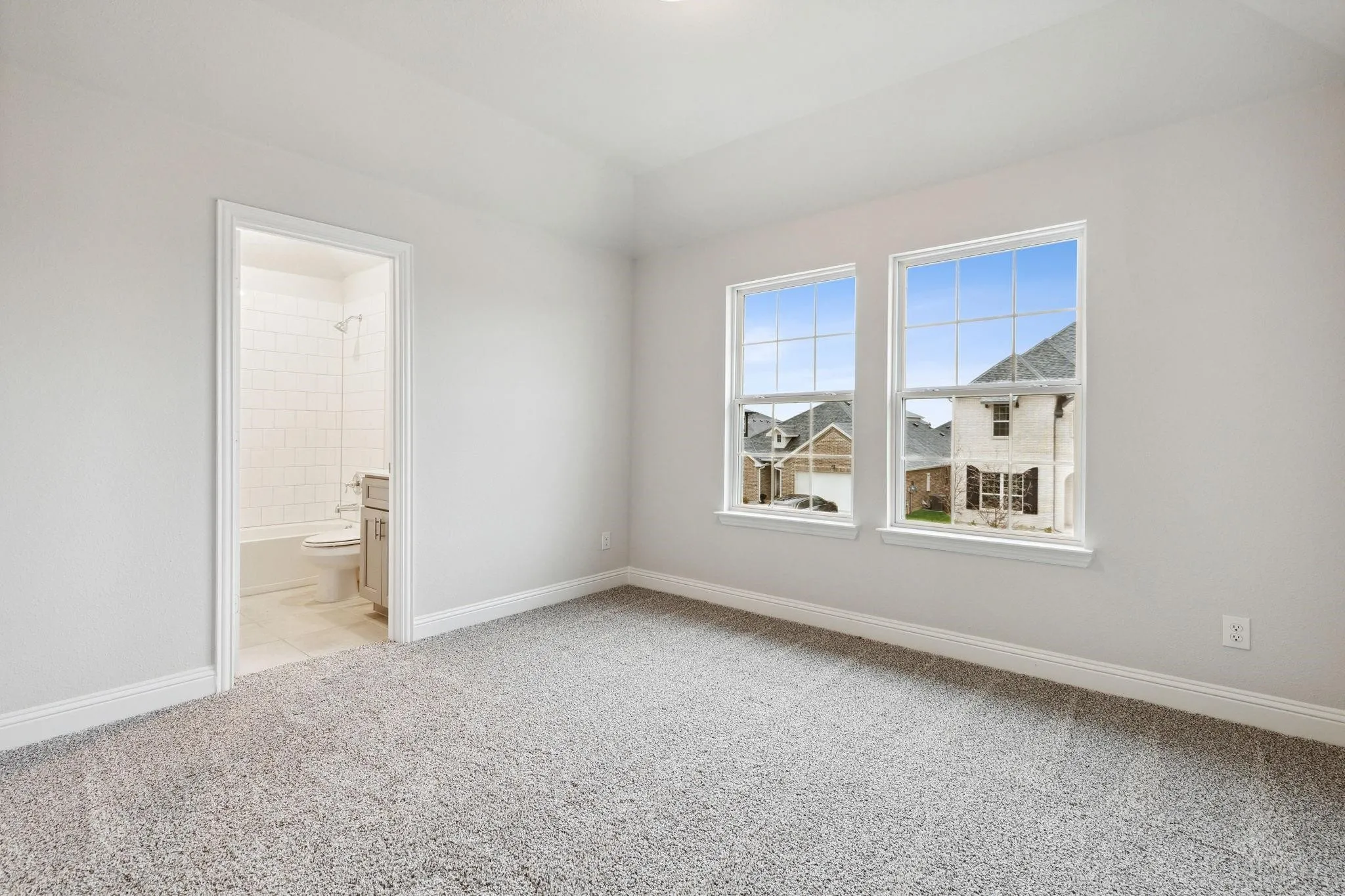 Unfurnished bedroom with light carpet and ensuite bath