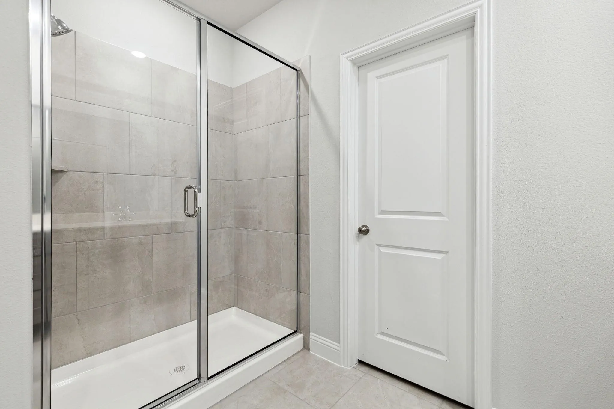 Bathroom with a shower with door and tile patterned floors