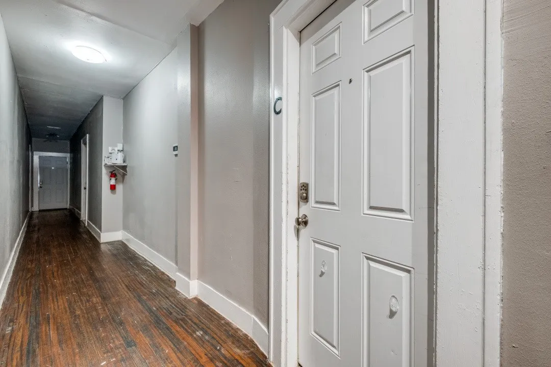 Entry door with paneling, metal hardware, and white trim