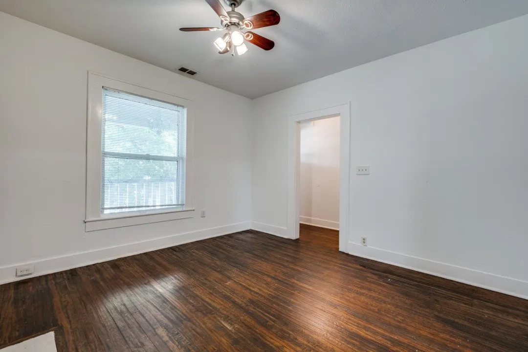 Hardwood flooring, painted walls, ceiling fan with light fixture, and window with white trim