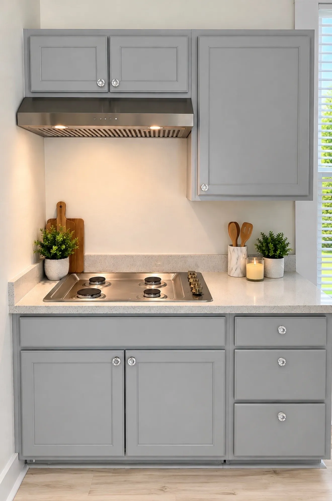 Kitchen featuring light gray cabinetry, stainless steel range hood, built-in cooktop, light-toned countertop, and wood-finish flooring