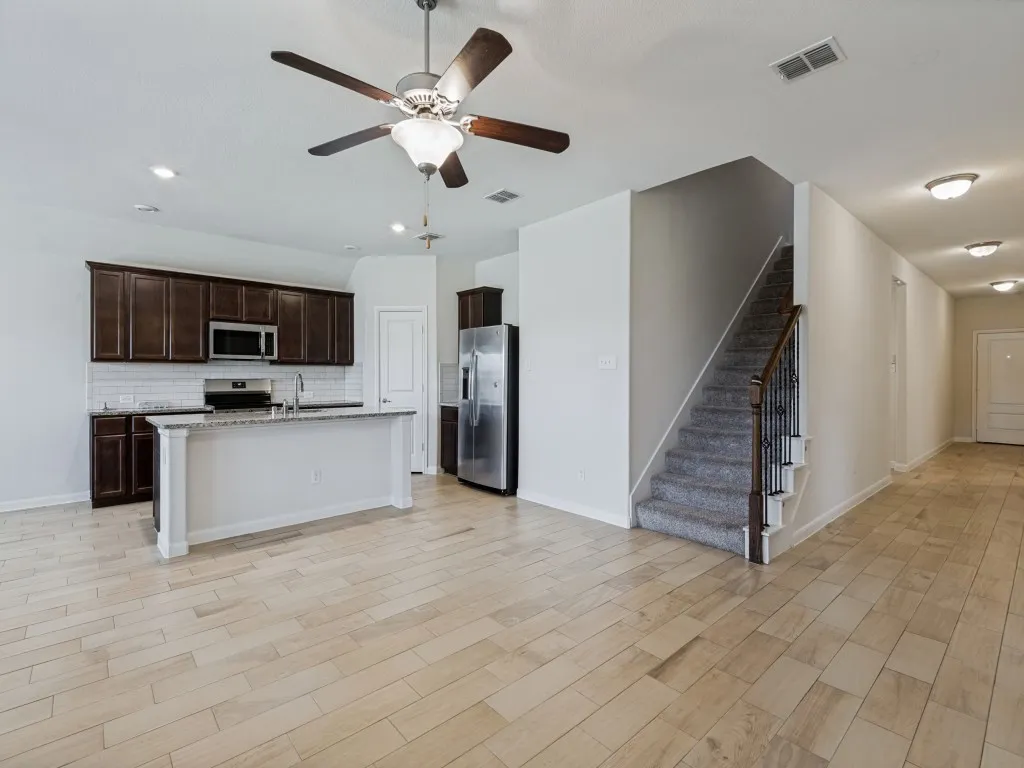Open-concept kitchen with dark wood cabinetry, white subway tile backsplash, and a central island