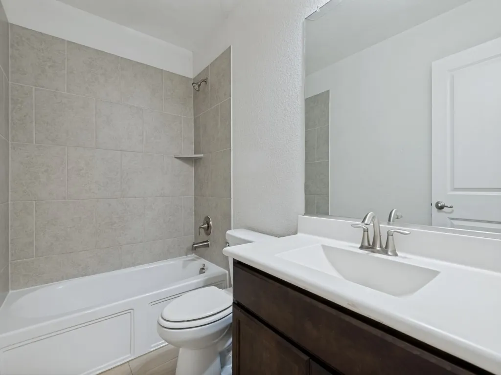 Bathtub with subway tile surround, integrated shower shelf, and brushed nickel fixtures