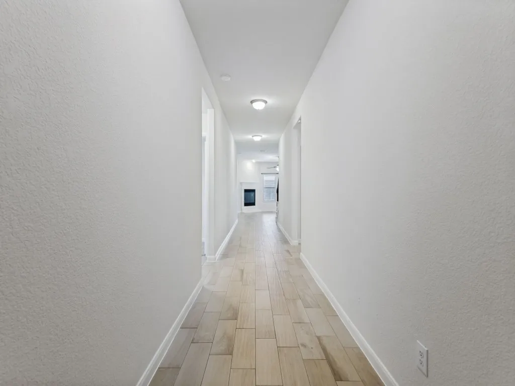 Long hallway featuring recessed lighting and wood-finish flooring