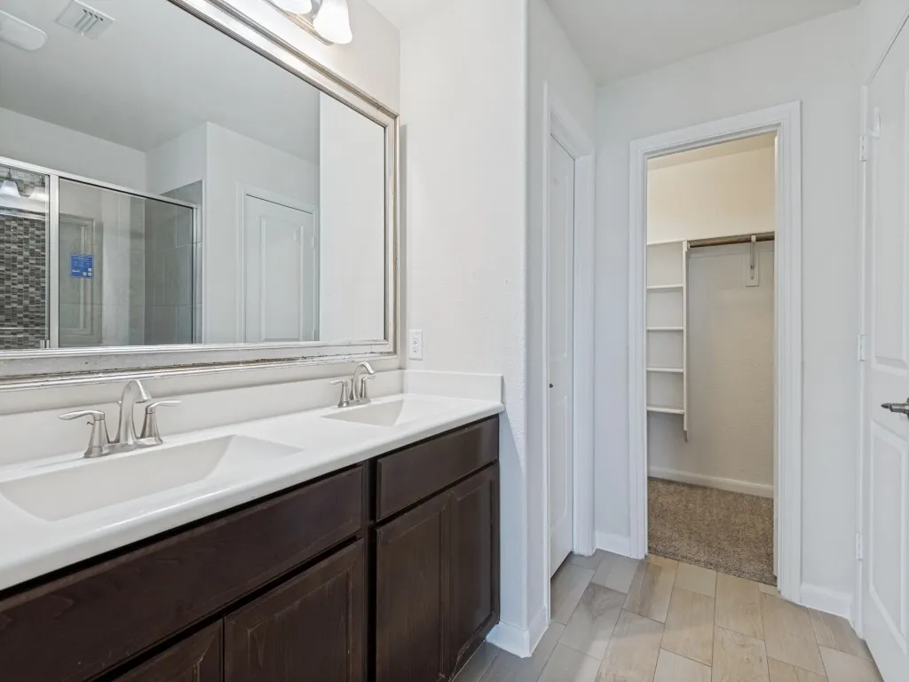 Double vanity with integrated sinks, dark wood-finish cabinetry, and brushed nickel fixtures