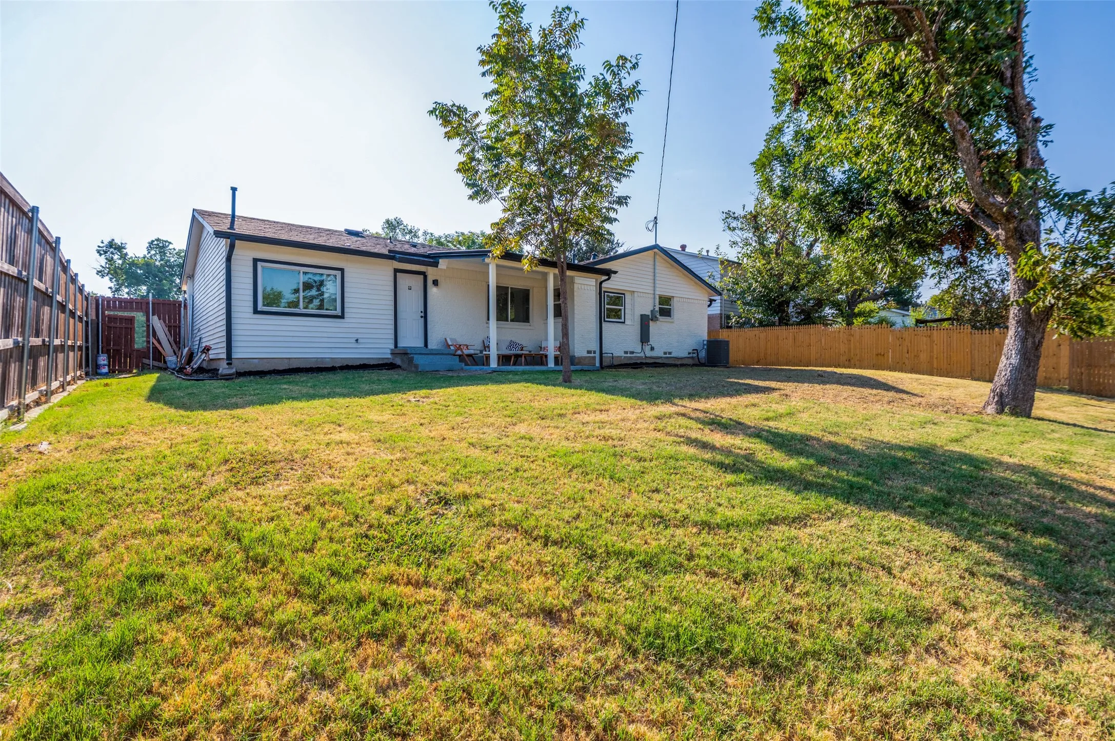 Expansive backyard featuring a fenced perimeter, mature trees, and a covered patio