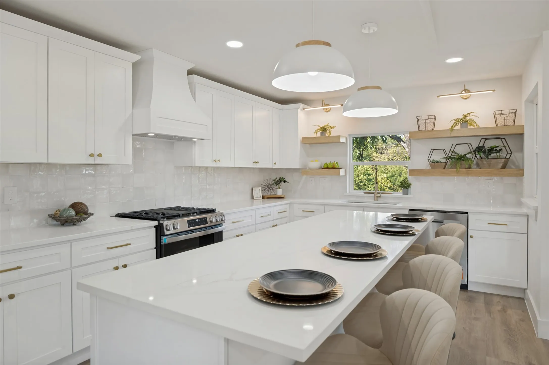 Spacious kitchen featuring white cabinetry, a large center island with seating, a built-in range, and wood-finish open shelving