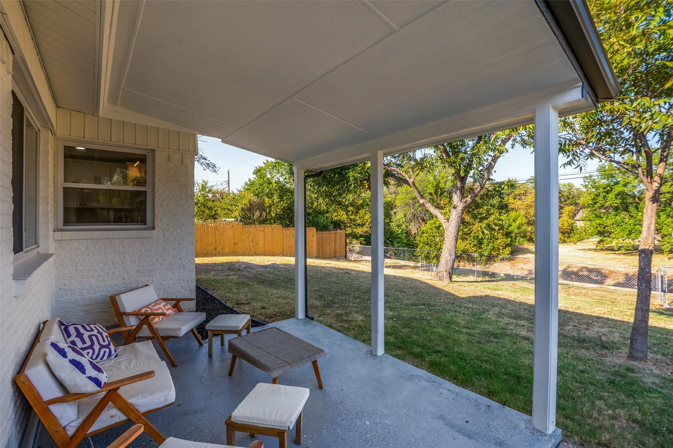 Covered patio with a concrete surface, white painted brick exterior, and a fenced backyard