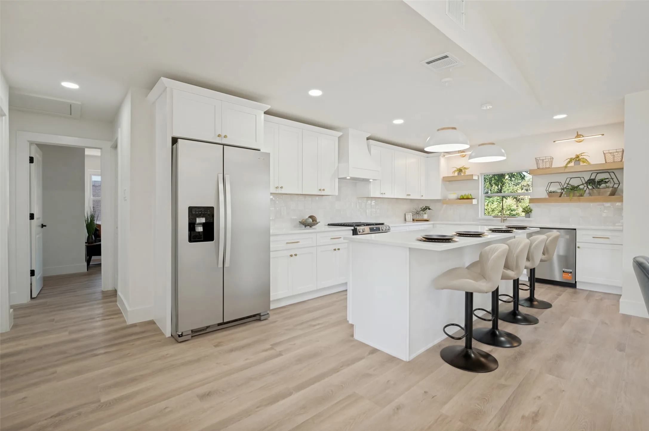 Kitchen featuring white cabinetry, a large central island, stainless steel appliances, wood-finish flooring, and recessed lighting