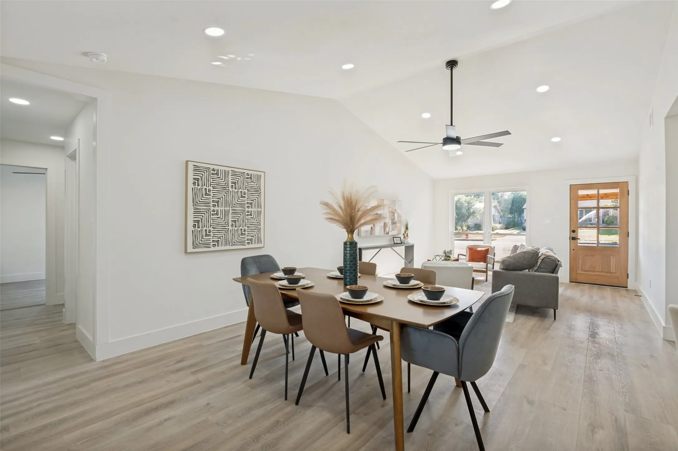 Open-concept living space with vaulted ceilings, recessed lighting, a modern ceiling fan, wood-finish flooring, and a paneled front door with glass inserts