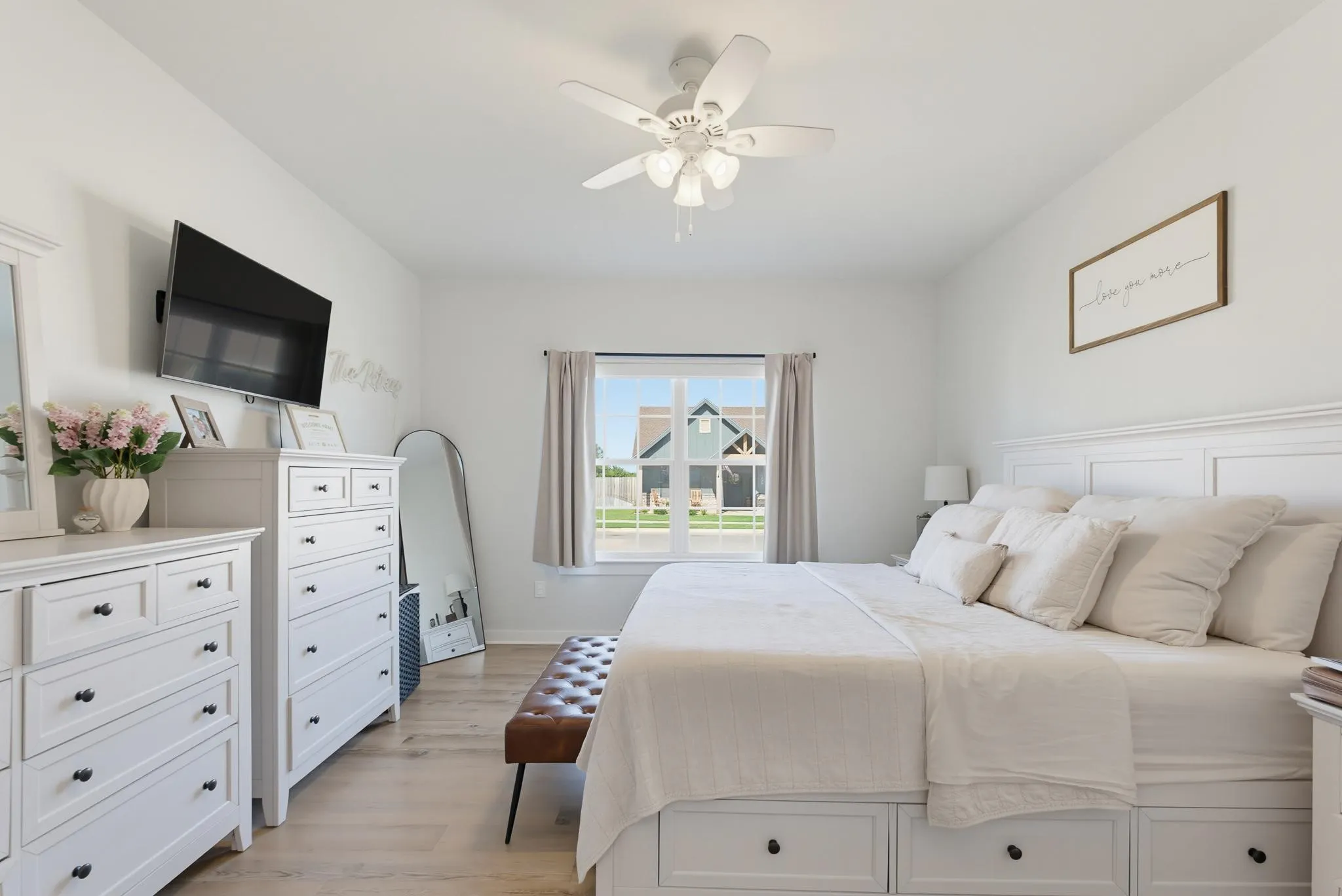 Vaulted ceiling with a ceiling fan, light wood-finish flooring, recessed window, and white built-in storage drawers