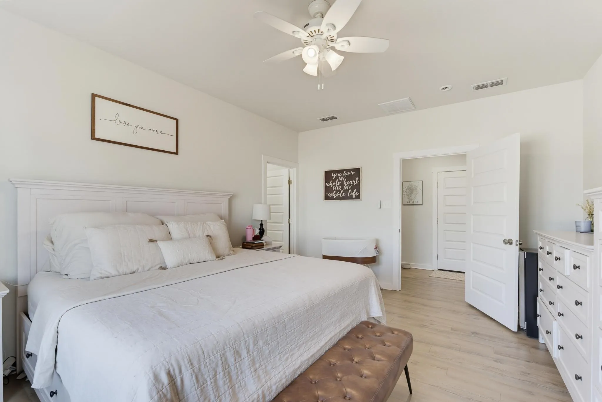 Spacious room featuring light wood-finish flooring, a ceiling fan with integrated lighting, and multiple paneled doors