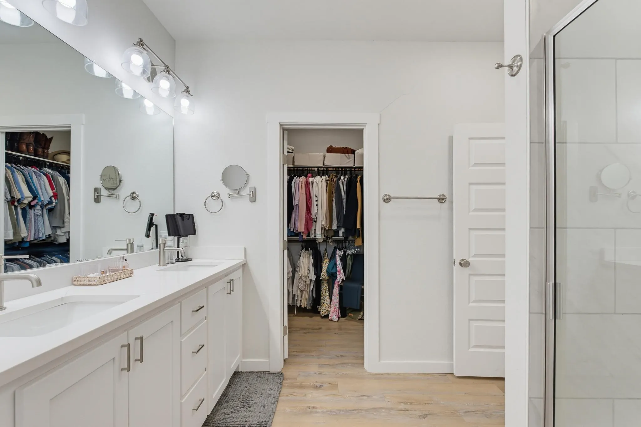 Dual vanity with white cabinetry and integrated sinks, brushed nickel fixtures, contemporary overhead lighting, and wood-finish flooring