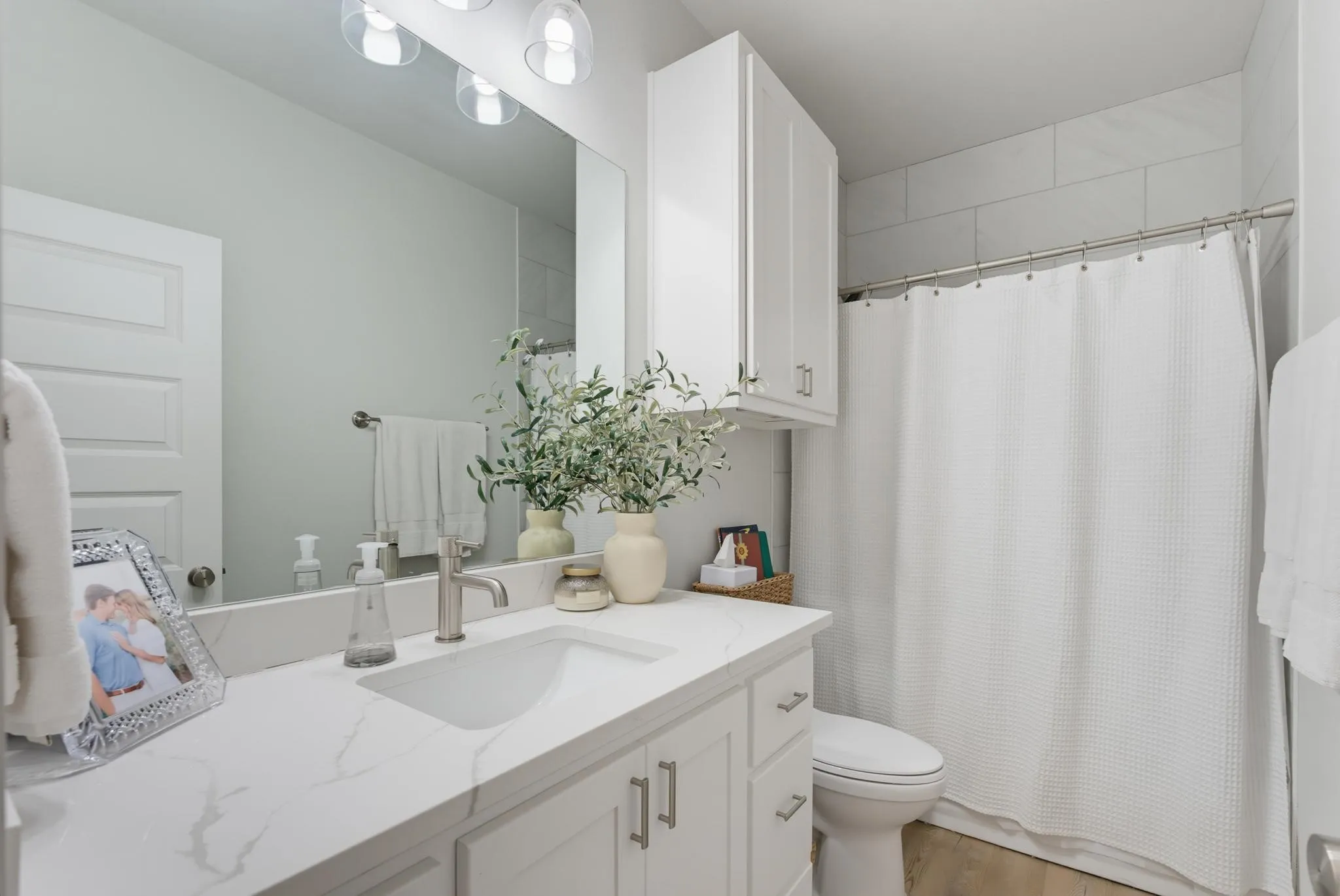 White vanity with a single basin, brushed nickel faucet, and integrated overhead lighting