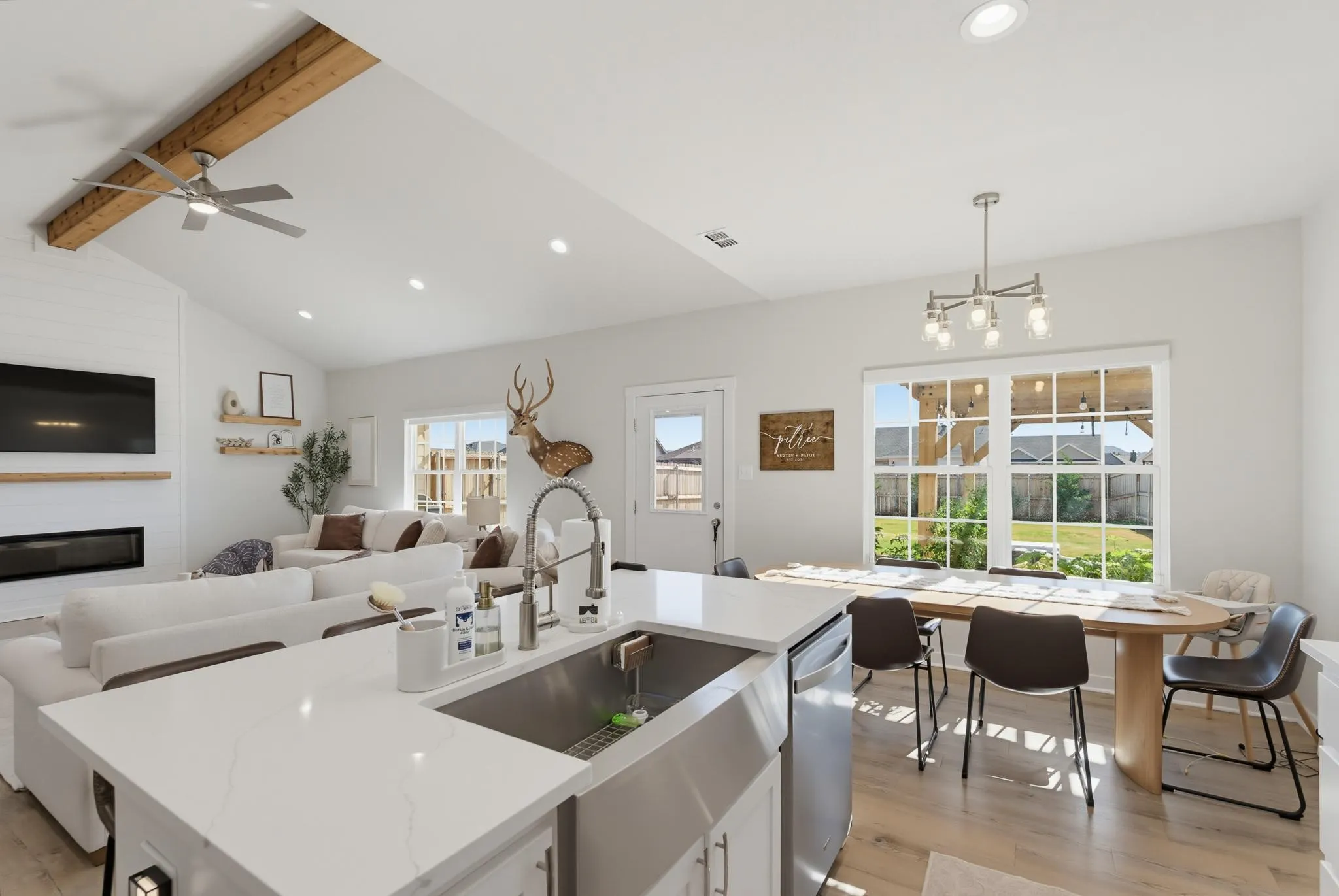 Open-concept living area with vaulted ceilings, exposed wood beam, recessed lighting, and wood-finish flooring