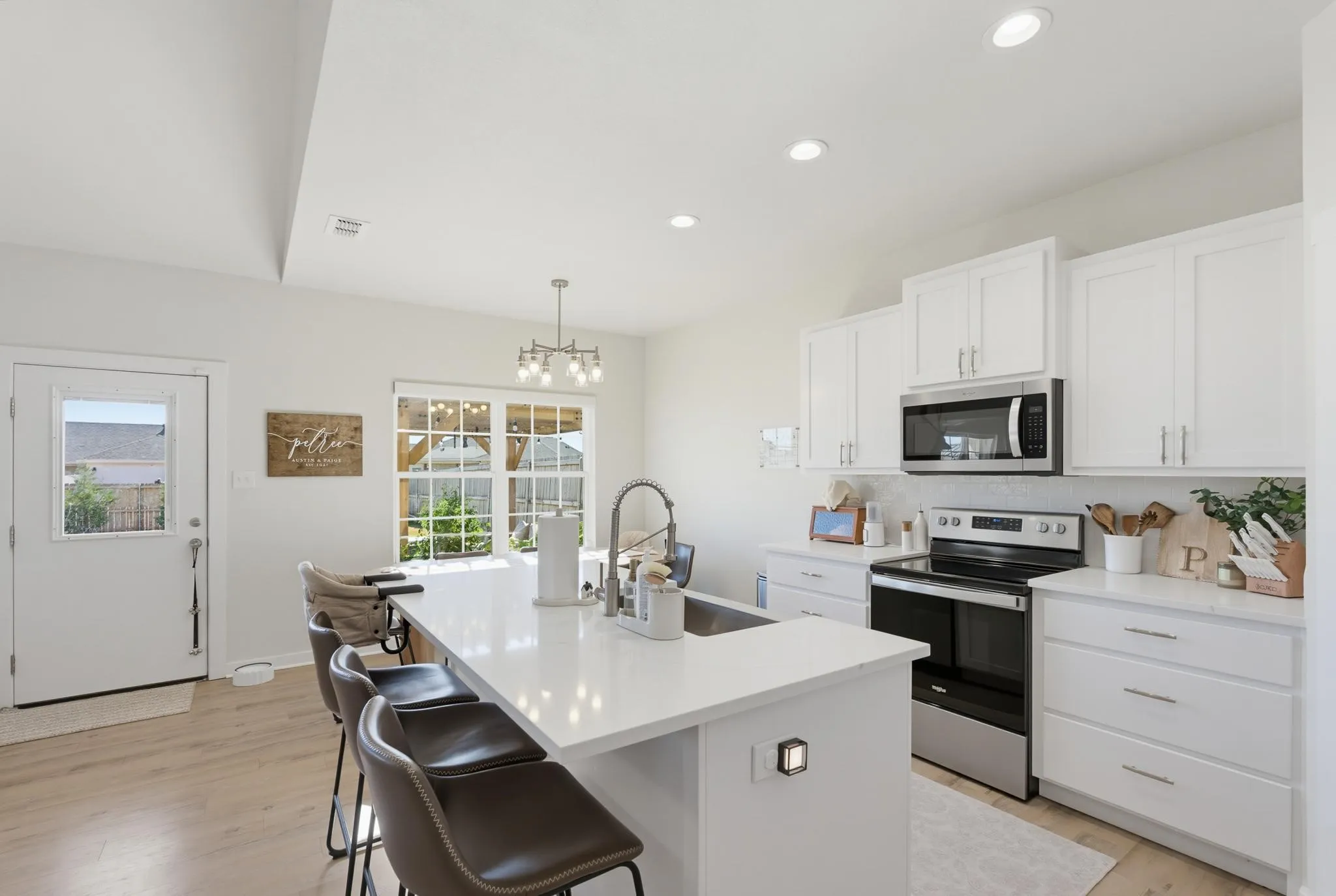 Kitchen featuring light wood-finish flooring, white cabinetry, stainless steel appliances, and a central island with an integrated sink