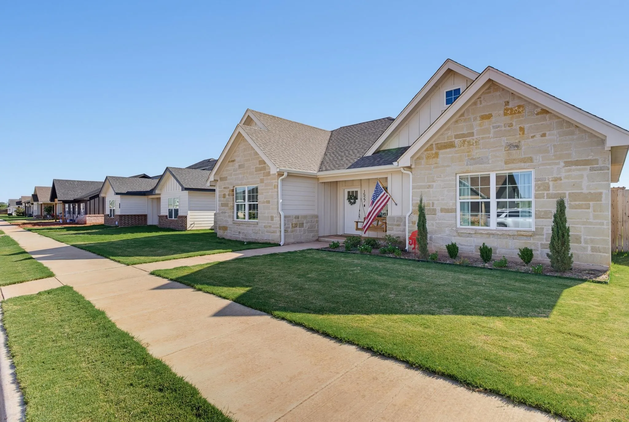 Stone and siding exterior with a covered front porch, gabled roofline, and landscaped front yard