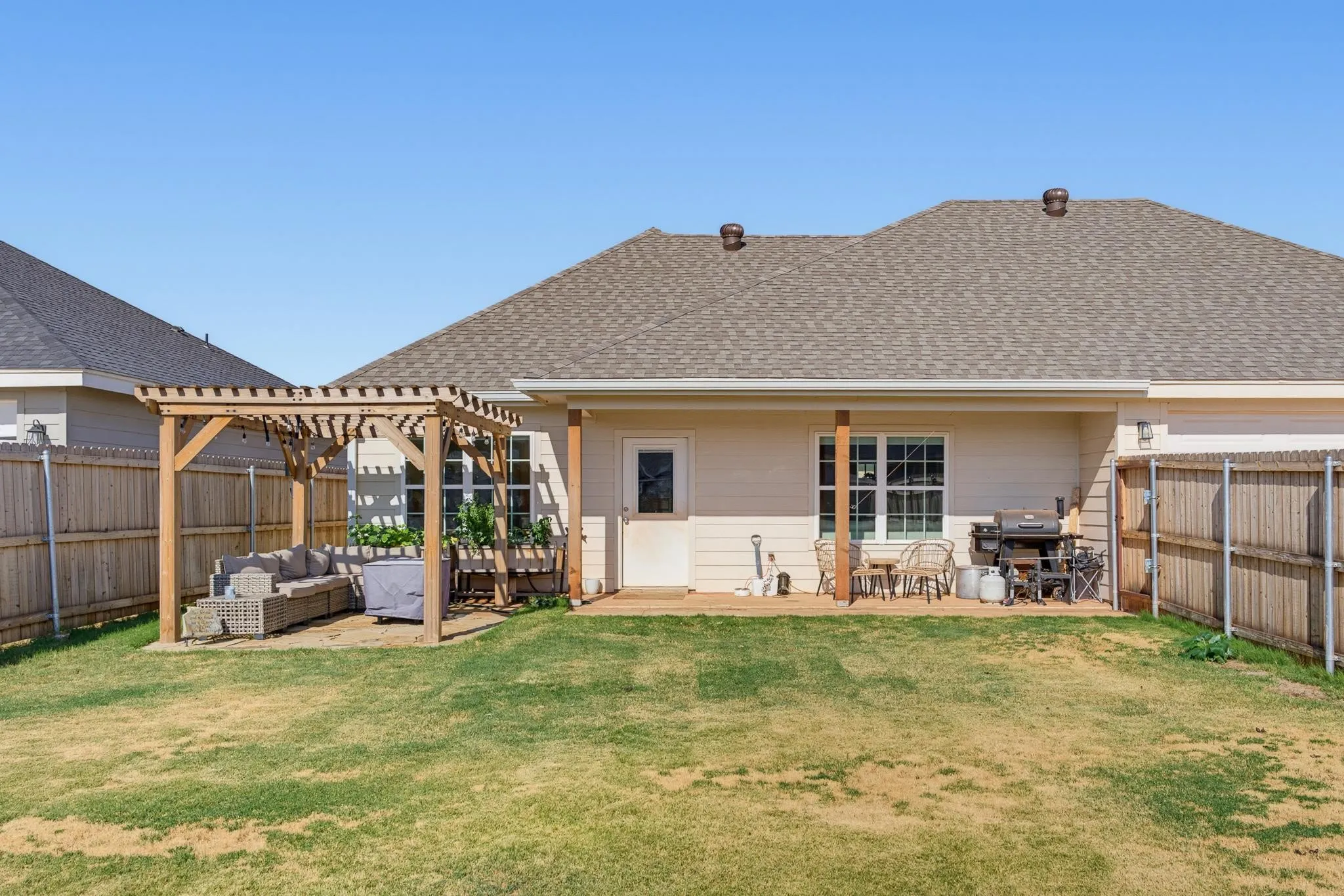 Expansive backyard featuring a wood pergola and privacy fencing