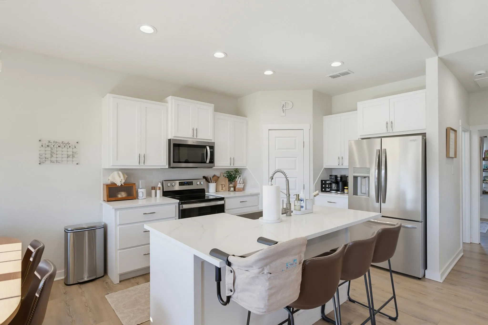 Kitchen featuring white cabinetry, stainless steel appliances, a center island with countertop seating, recessed lighting, and wood-finish flooring