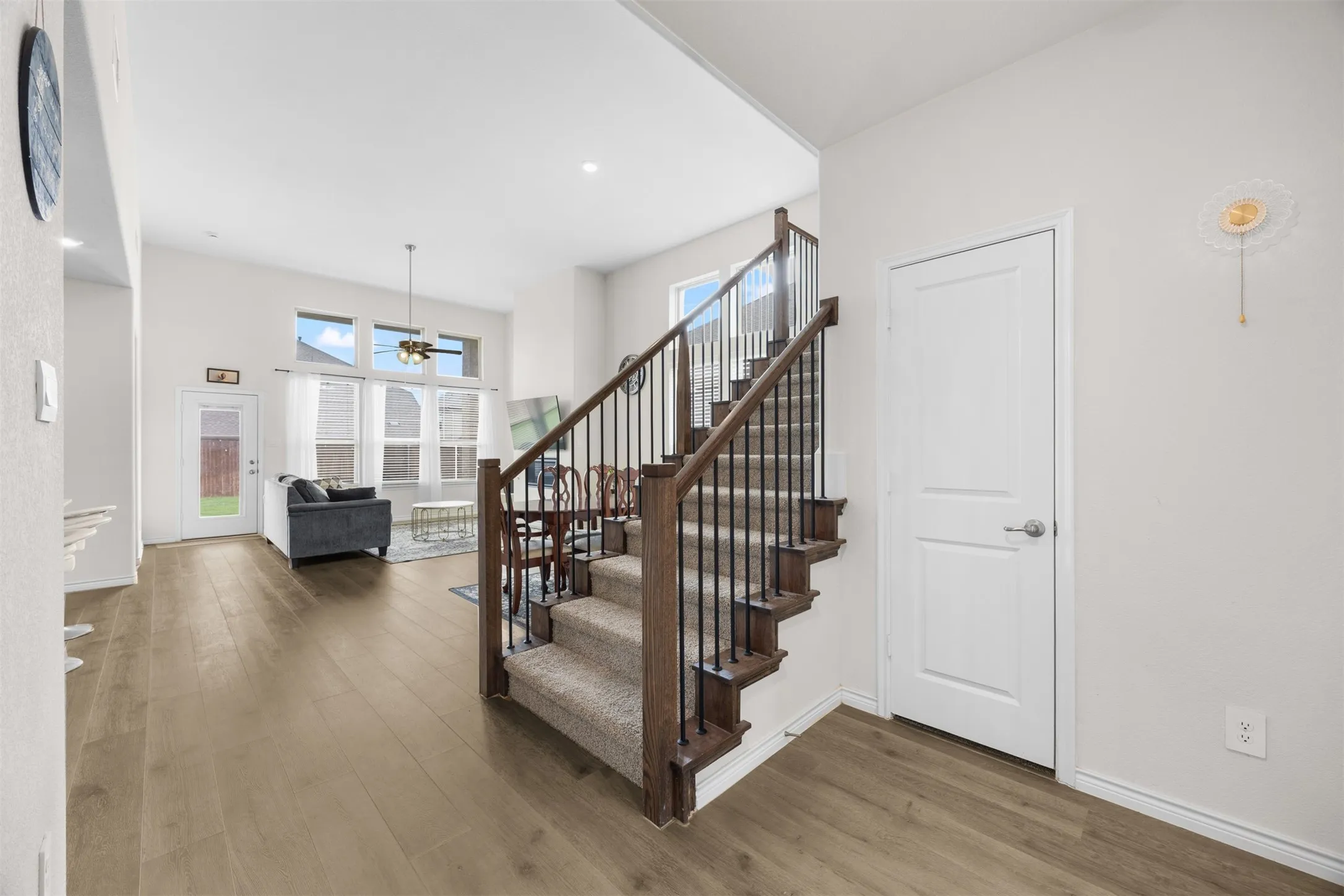 Wood-finish flooring throughout, with a carpeted staircase featuring dark wood newel posts and black metal balusters
