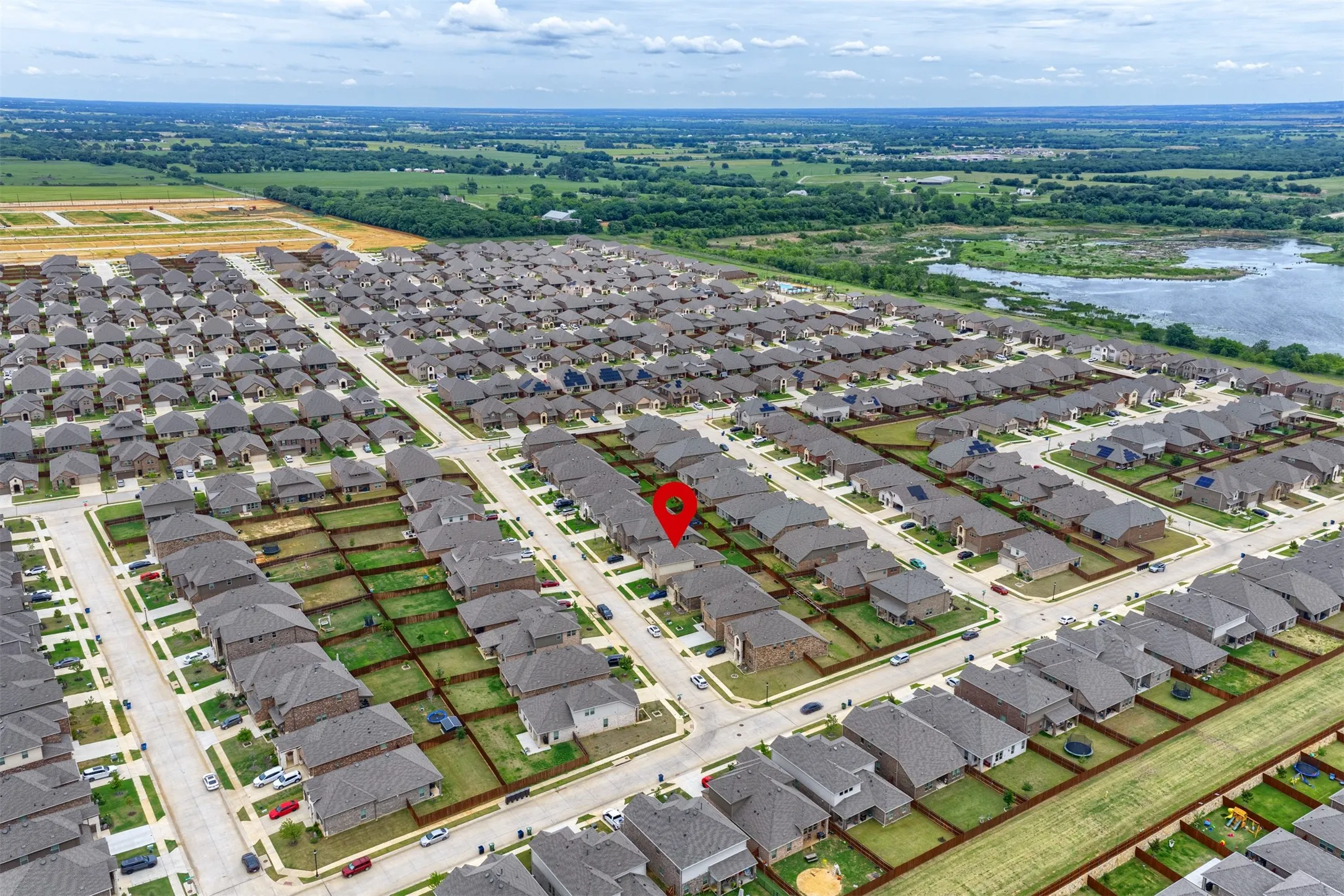 Expansive residential development featuring uniform homes, paved streets, and surrounding green spaces