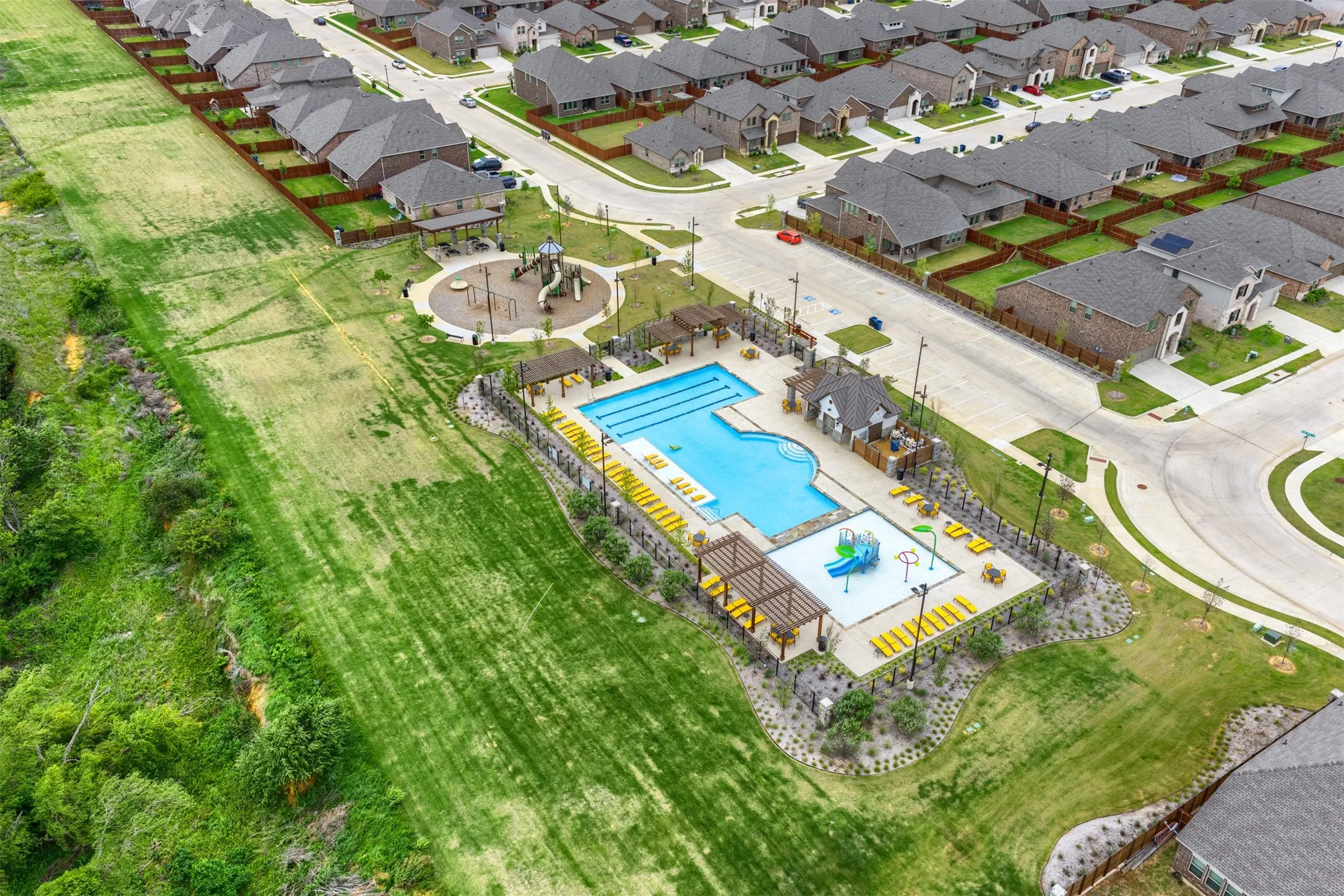 Community amenities include a multi-level swimming pool, a children's splash pad, a playground with shade structures, and an adjacent recreational area
