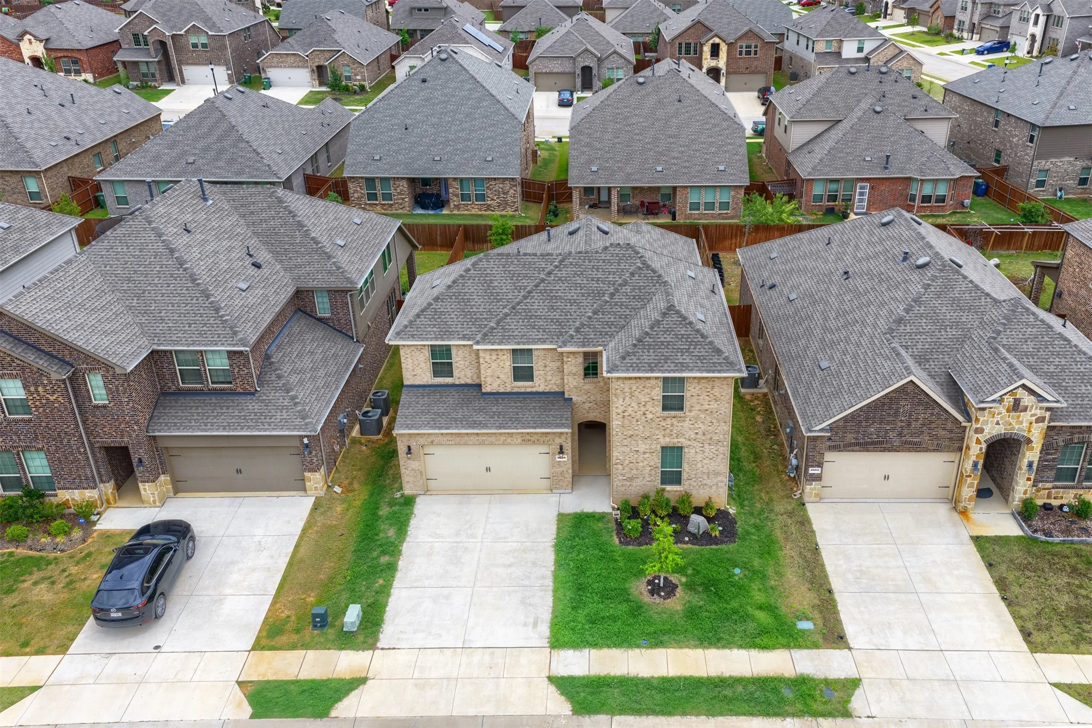 Two-story brick exterior with a gray shingle roof, attached two-car garage, and a concrete driveway