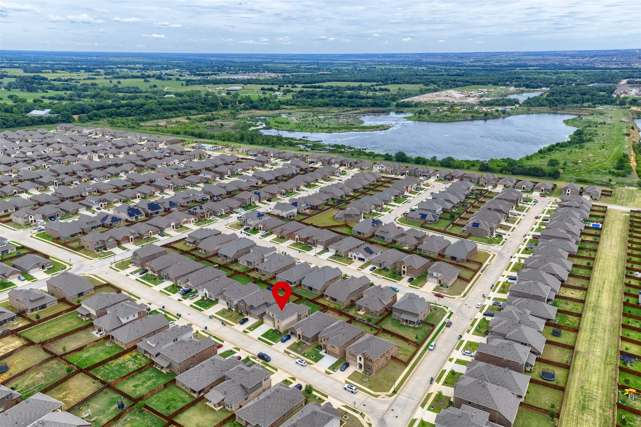 Aerial perspective of a developed residential community with surrounding green spaces and a prominent body of water
