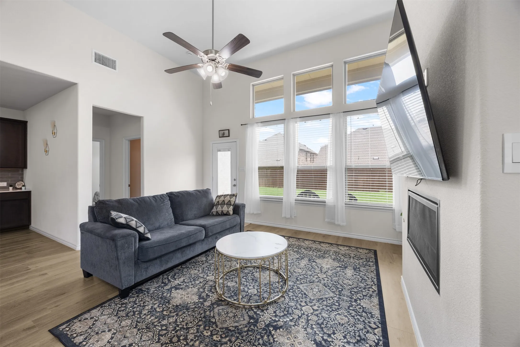 Living area with high vaulted ceilings, wood-finish flooring, and a ceiling fan