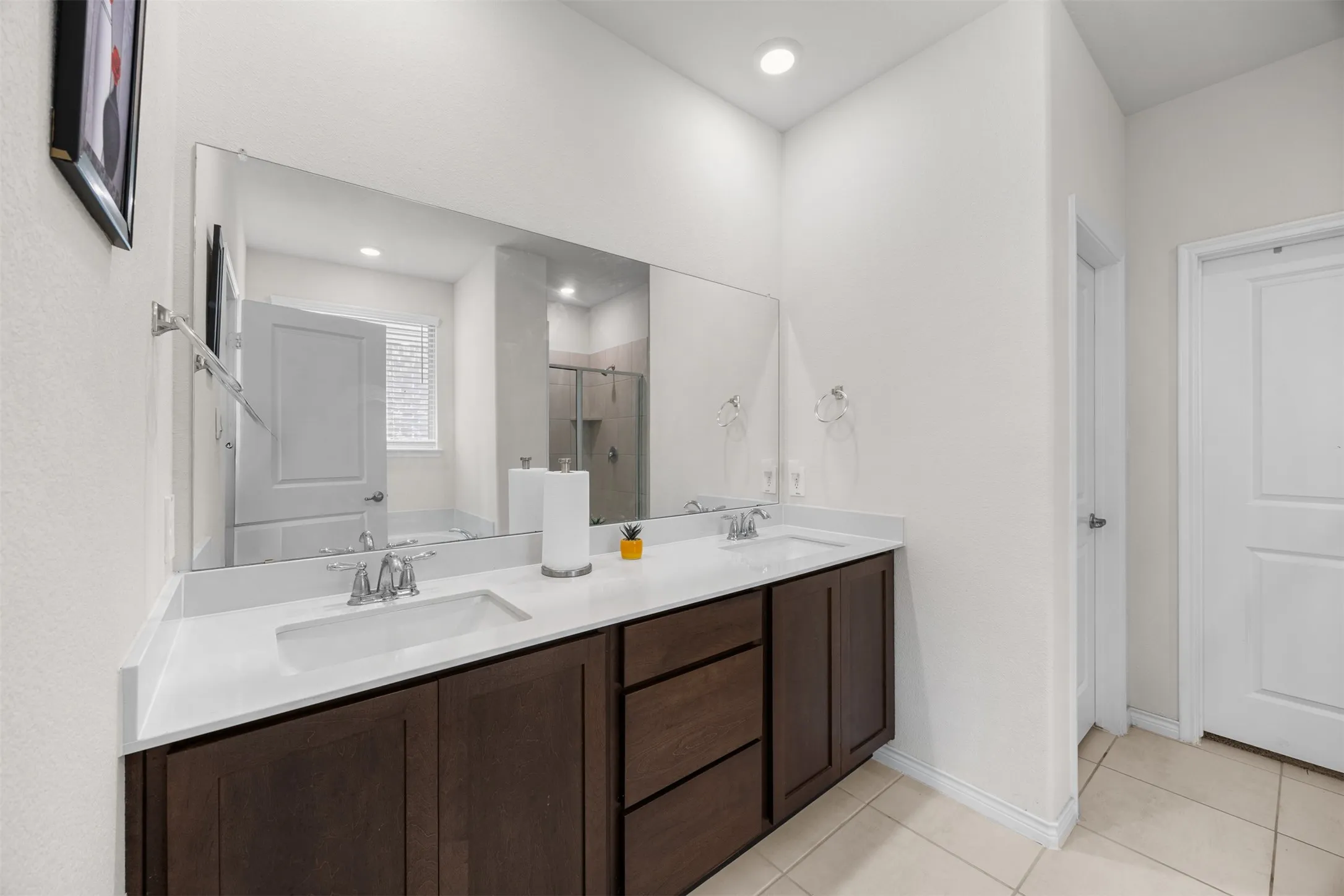 Dual vanity with undermount sinks, chrome fixtures, dark wood-finish cabinetry, and a large wall-mounted mirror