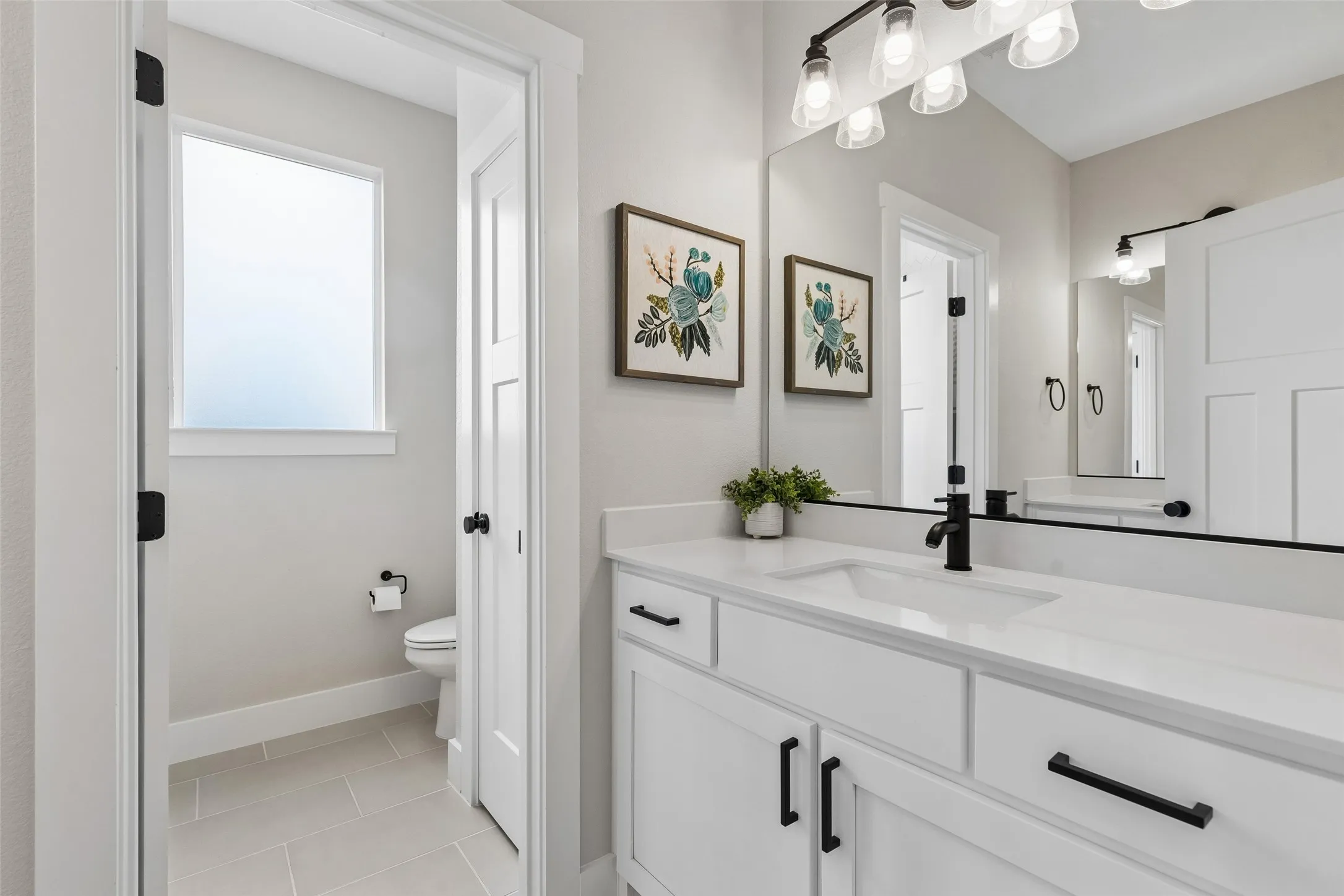 White vanity with integrated sink, matte black faucet, and full-width mirror