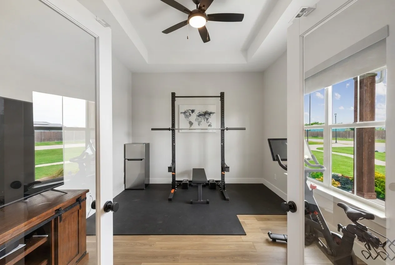 Tray ceiling with a ceiling fan, French doors, wood-finish LVP flooring, and a large window