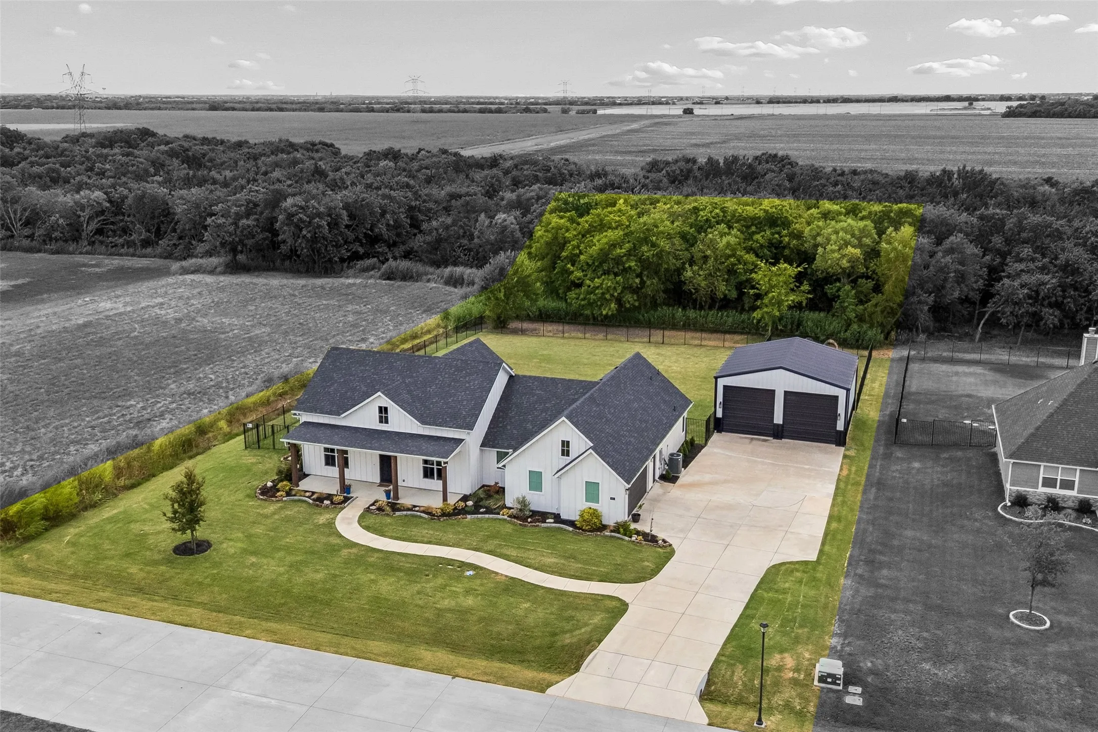White exterior with a dark roof and covered porch. Approximately one-quarter acre of wooded property to ensure long-term privacy.