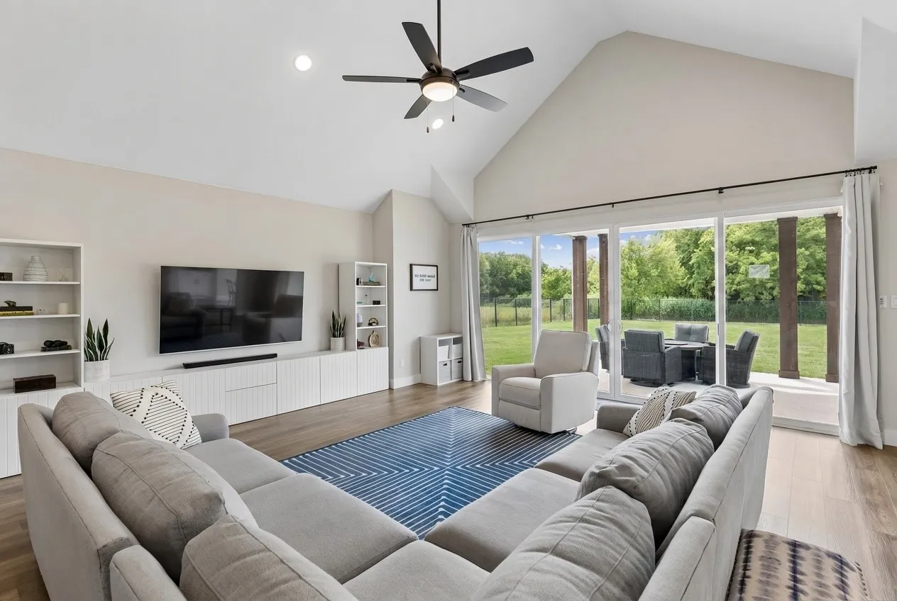 Vaulted ceiling with recessed lighting, large format sliding glass doors, wood-finish LVP flooring, and a ceiling fan